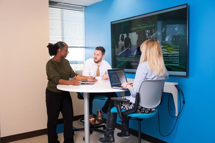 Three business professionals chat during a meeting