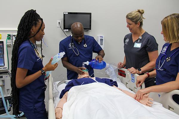 Male and female students practice respiratory care skills on a high-fidelity medical maniken